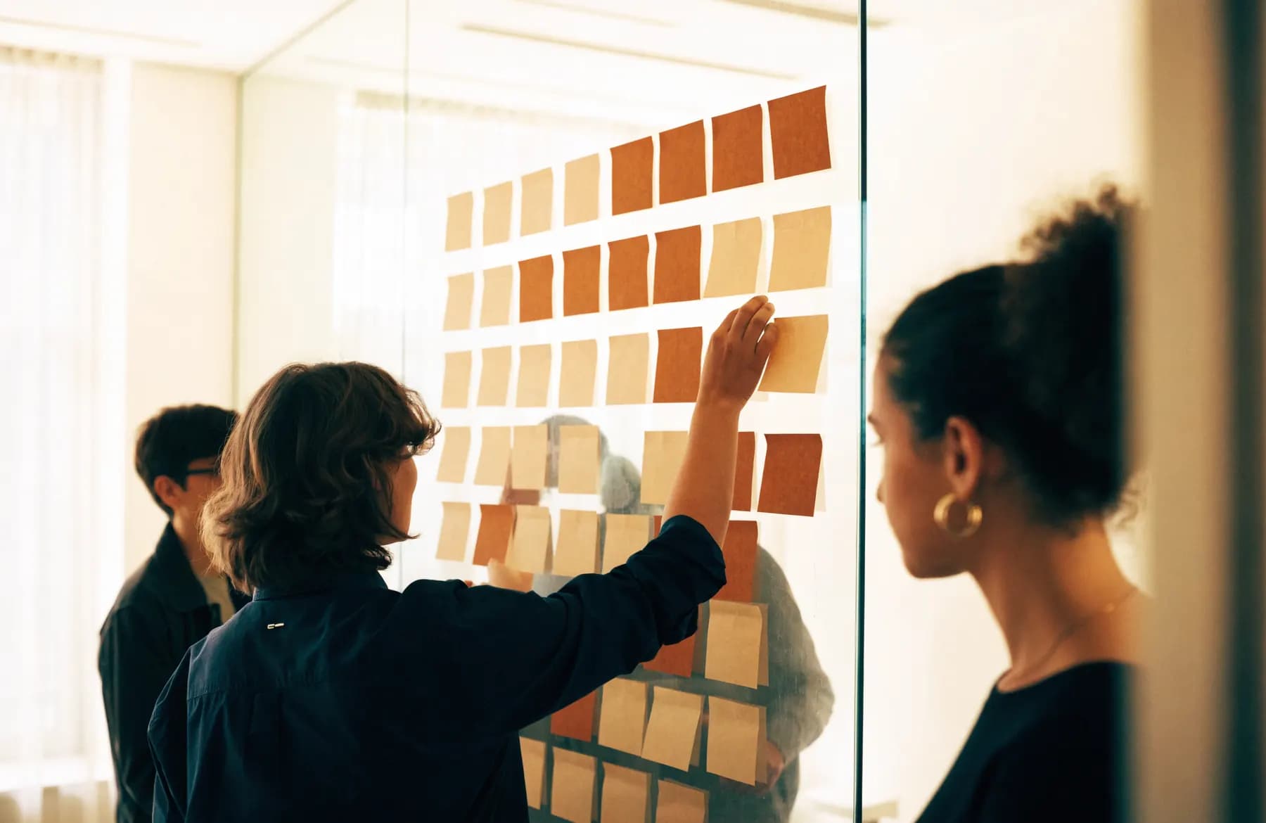 A discovery workshop with paper notes arranged in columns on a glass wall