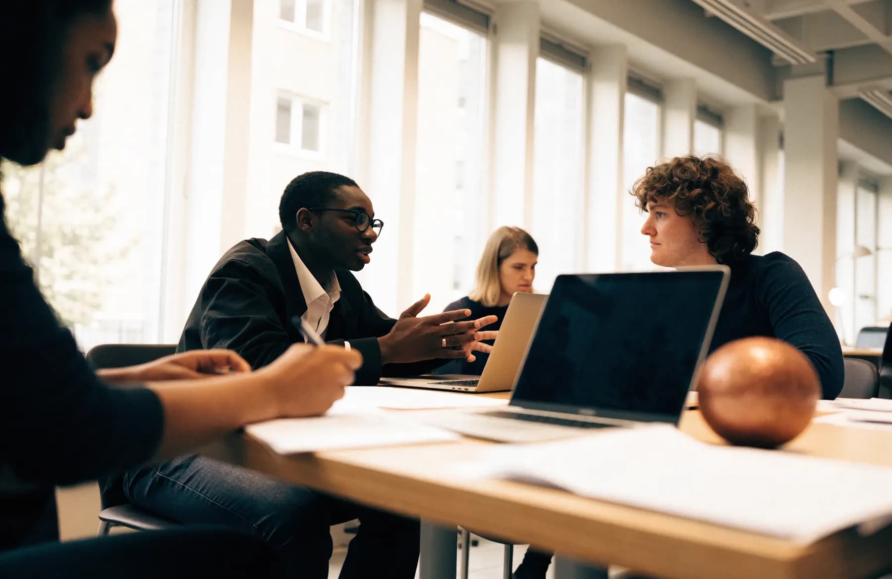 A small team working together around a meeting table with laptops and printed documents